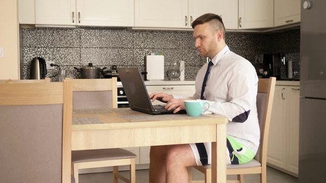 Home Office. Young businessman is working intensively while sitting at the kitchen table. He communicates simultaneously on skype and mobile phone.
