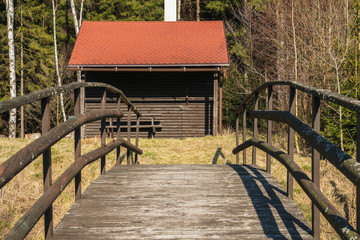 Obraz premium Fisherman's house with a wooden pedestrian bridge on a tiny island in the middle of the lake. Autumn view. Czech Republic