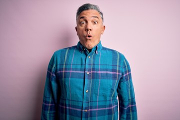 Middle age handsome grey-haired man wearing casual shirt over isolated pink background afraid and shocked with surprise expression, fear and excited face.