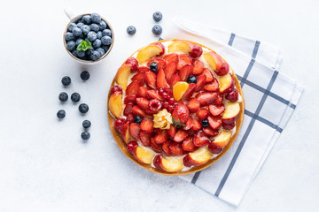 Homemade open tart with strawberries, raspberries, blueberries and grapes on a grey background. Homemade cake. The concept of healthy and delicious food. Top view, copy space.