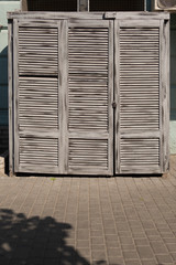 Wooden doors with gray aged blinds on the facade of the house.