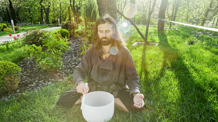 A qigong master conducts meditation using a gong and Crystal bowl, Crystal Tibetian singing bowl, a...