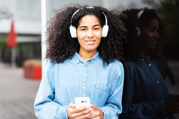 Portrait einer lachenden jungen Frau mit Kopfhörern in der Stadt 