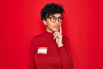 Young beautiful african american afro woman using sticker with presentation message serious face...