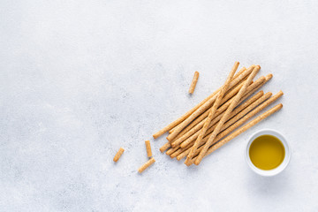 Organic Italian grissini or salted bread sticks and bread lying on a gray background. Fresh Italian snack for apero. Top view, copy space