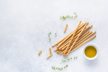Organic Italian grissini or salted bread sticks and bread lying on a gray background. Fresh Italian snack for apero. Top view, copy space