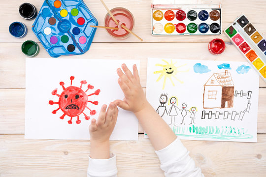 A child draws a coronovirus and his family on a piece of paper. Coronovirus and family at home. The drawing was made by a child using color paints. Children's drawing. View from above