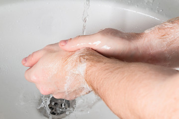 Fototapeta premium Man use soap and washing hands under the water tap. Hygiene concept hand detail.