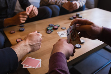 Several men are playing poker in a cafe, holding cards in their hands.