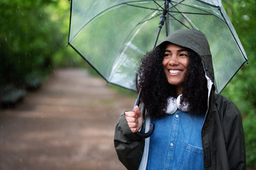 Eine junge Frau mit Regenjacke und Regenschirm draußen im Regen 