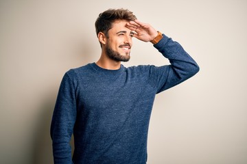 Young handsome man with beard wearing casual sweater standing over white background very happy and...