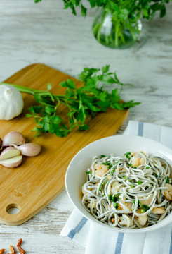 Bol blanco de gulas con gambas, ajos, perejil, guindillas sobre mesa blanca