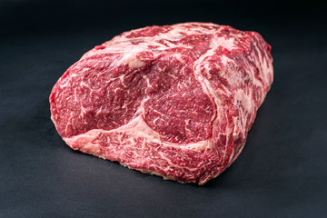 Raw dry aged wagyu entrecote beef steak roast as closeup on a black background with copy space