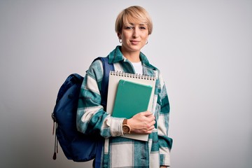 Obraz premium Young blonde student woman with short hair wearing backpack and holding university books with a confident expression on smart face thinking serious