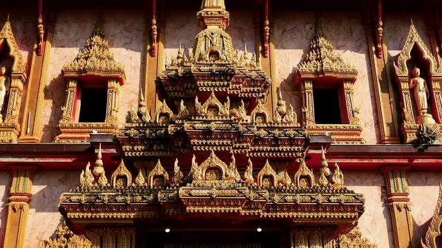 Golden coated traditional ornamental decorative elements at outer side of Thai temple at Phuket island.