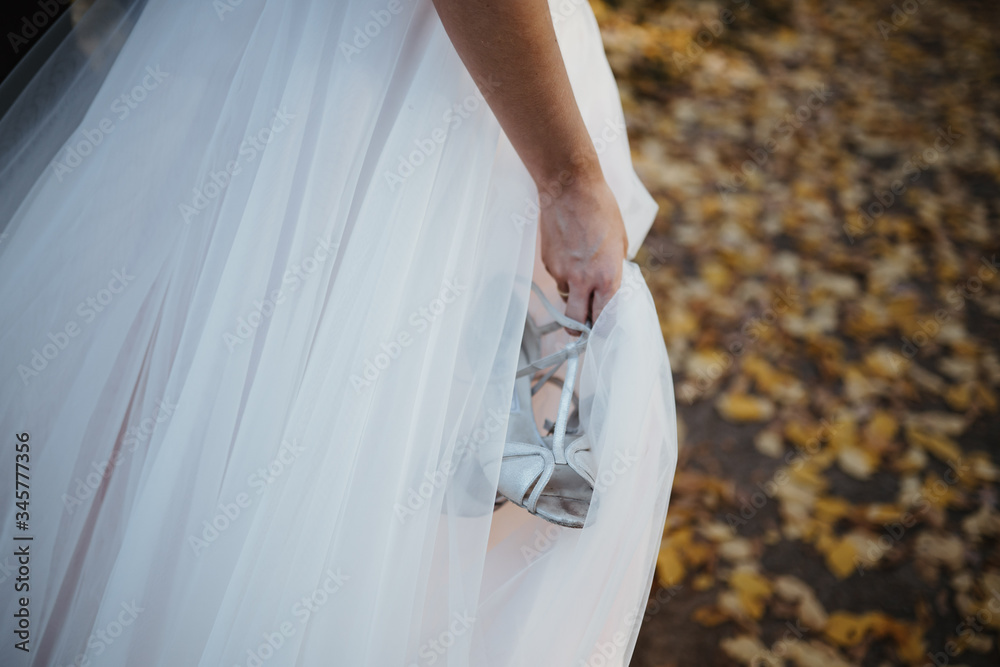 Wall mural photo of a bride holding her shoes in her hand