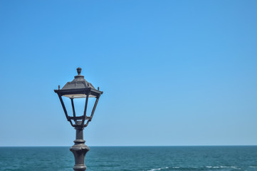 black antique street light on a background of blue seascape