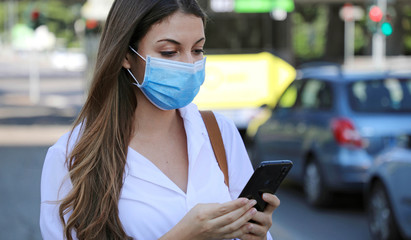 COVID-19 Pandemic Coronavirus Mobile Application - Young Woman Wearing Surgical Mask Using Smart...