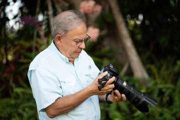 Older photographer looking at his camera