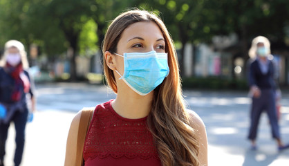 COVID-19 Social Distancing Woman in city street wearing surgical mask against disease virus...