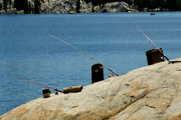 Absentee Fishing. Hands free fishing with poles propped up by tackle box, cart and cooler, Lake...