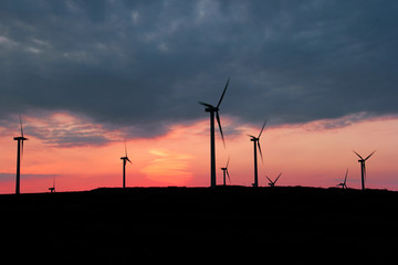 Turbines on a hill with a sunset background