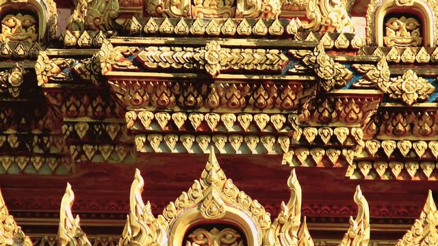 Golden coated traditional ornamental decorative elements at outer side of Thai temple at Phuket island.