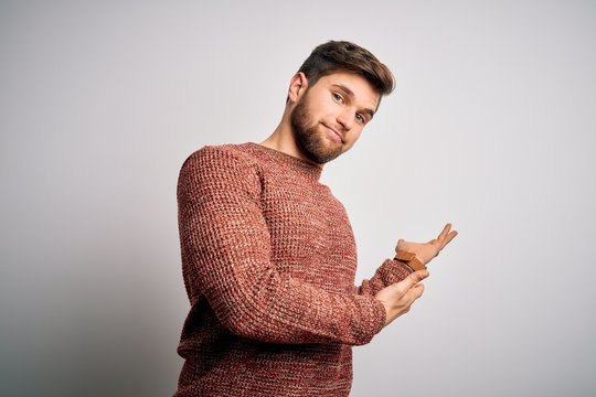 Young blond man with beard and blue eyes wearing casual sweater over white background Inviting to enter smiling natural with open hand