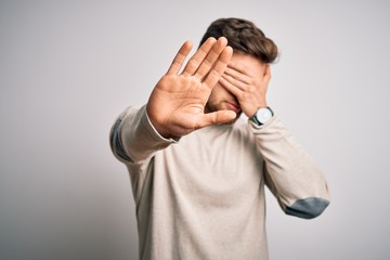 Young handsome blond man with beard and blue eyes wearing casual sweater covering eyes with hands and doing stop gesture with sad and fear expression. Embarrassed and negative concept.
