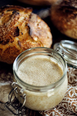 A jar with active rye sourdough for baking bread on a wooden table, close up