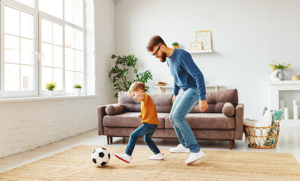 Father And Son Playing Football At Home.