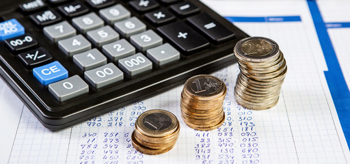 Close up of a calculator and coins on a business background