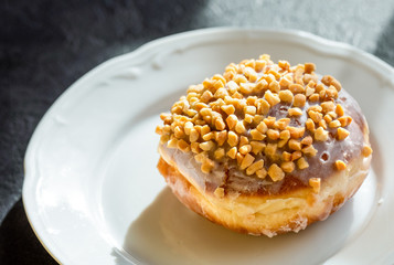 Donut with nuts on a white plate 