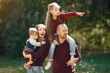 Fototapeta premium Family in a autumn park. Woman in a red sweater. Cute childrens with parents