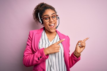 Young african american call center agent girl wearing glasses working using headset smiling and...