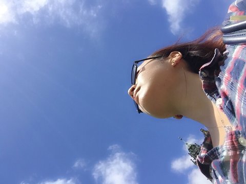 Directly Below Shot Of Woman Against Blue Sky