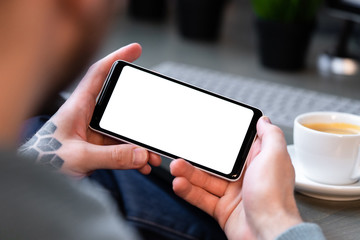 Man Holding Mobile Phone With Blank Screen and Drinking Coffee. Online Delivery, Shopping And Ordering in Social Distancing And Isolation. Copy Space. Empty Space