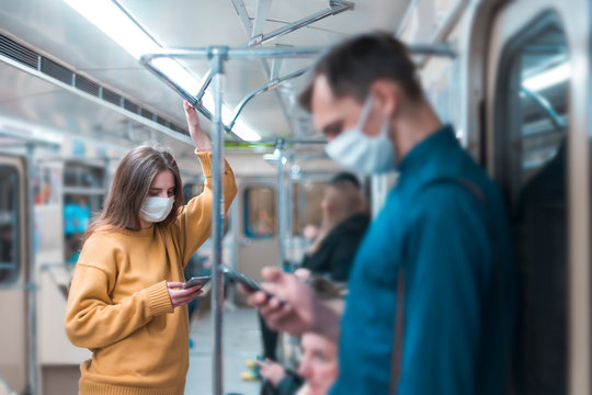 young woman in a protective mask standing in a subway car.