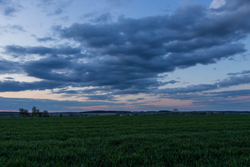 Obraz premium coloured sky with amazing clouds and green fields below 