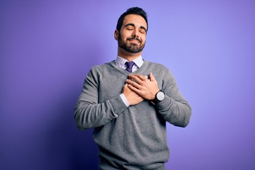 Handsome businessman with beard wearing casual tie standing over purple background smiling with hands on chest with closed eyes and grateful gesture on face. Health concept.