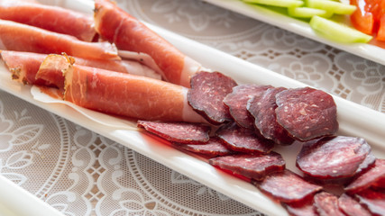 sausage and jerky cut into thin slices on a white plate