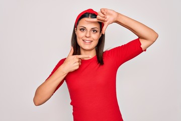 Obraz na płótnie Canvas Young beautiful brunette woman wearing casual t-shirt and diadem over white background smiling making frame with hands and fingers with happy face. Creativity and photography concept.