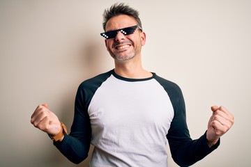 Young handsome man wearing funny thug life sunglasses meme over white background very happy and...