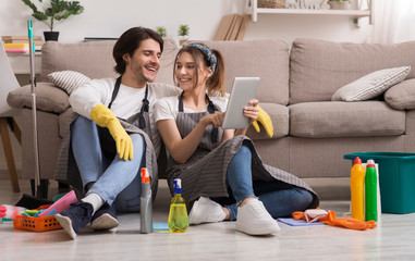 Cheerful Young Couple Relaxing With Digital Tablet After Cleaning Apartment