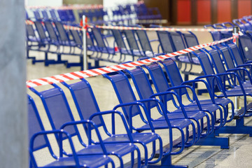 Stretched protective red tape on the chairs. It is forbidden to sit on public seats during the coronavirus pandemic, to protect people from infection.