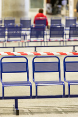 Stretched protective red tape on the chairs. It is forbidden to sit on public seats during the coronavirus pandemic, to protect people from infection. Vertical. 