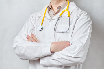 The doctor in a white coat folded his hands with a stethoscope on a white background.