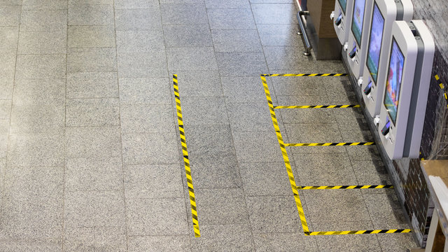 Secure marking of yellow lines on floor - measures for social distancing near self-service checkout counters in a fast food restaurant during coronavirus pandemic. Copy space. Top view. 