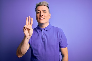 Fototapeta premium Young handsome modern man wearing casual purple t-shirt over isolated background showing and pointing up with fingers number three while smiling confident and happy.