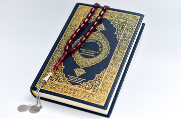 The Islamic holy book, Quran English Translation  and red rosary beads on white background. Arabic...
